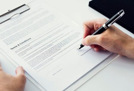 closeup-hand-signing-paper-workspace